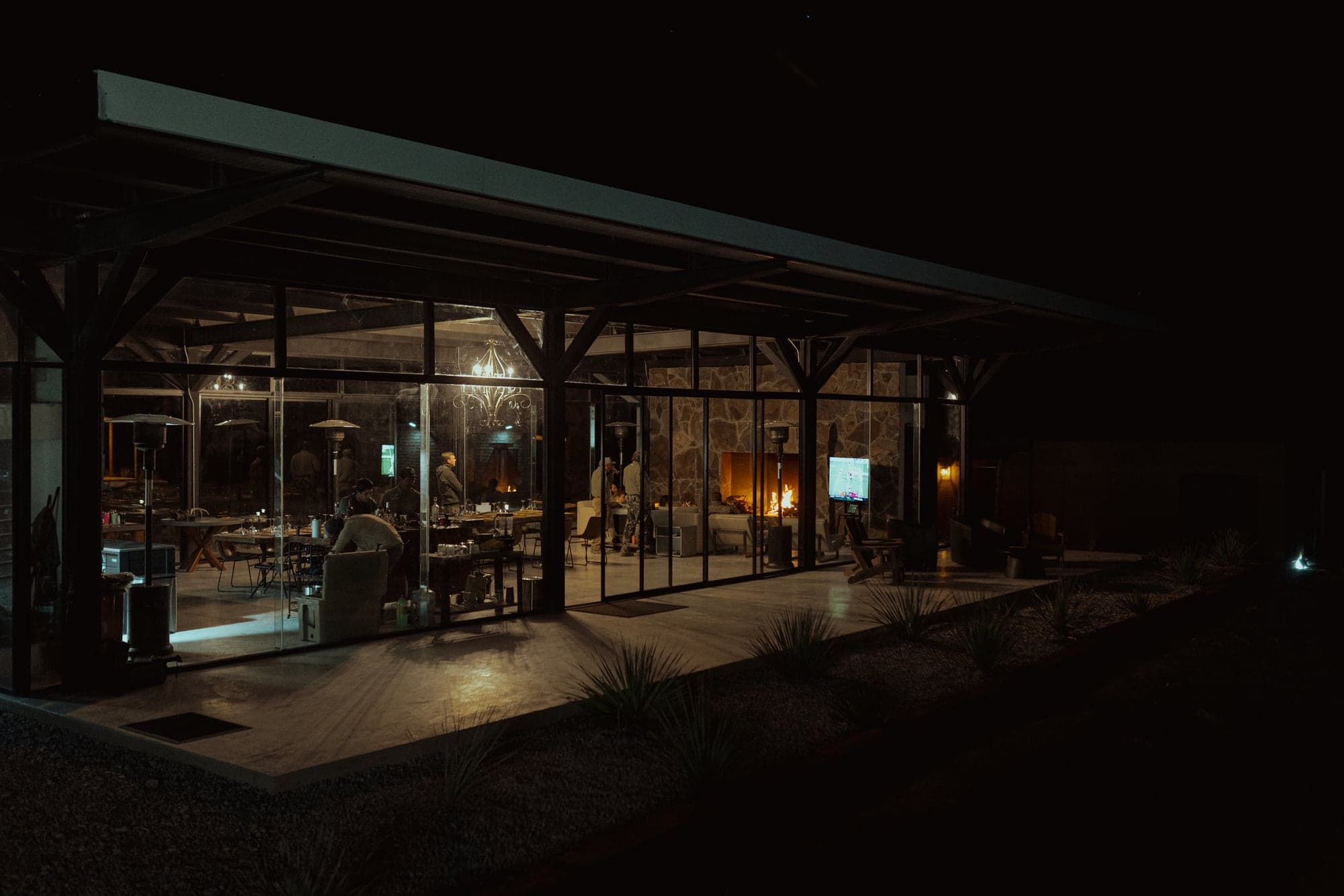 The glass-walled lodge glowing warm at night against the desert dark